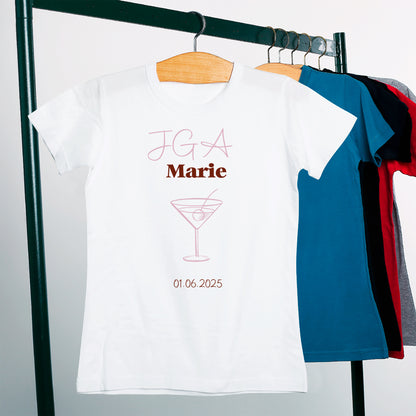 Junggesellinnenabschieds-T-Shirt in Weiß mit Text „JGA Marie“, Cocktailglas-Symbol und Datum 01.06.2025, rosa Akzente.