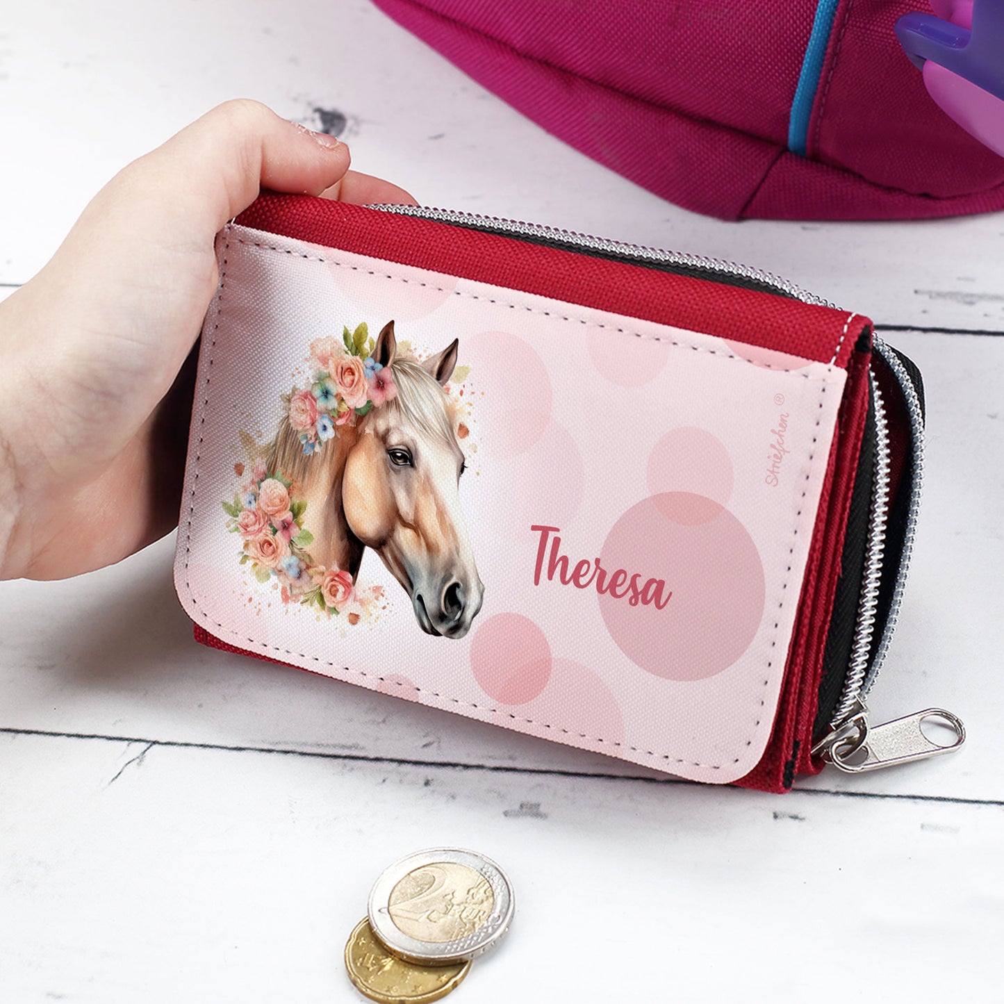 Kinder-Geldbörse mit Pferdemotiv und Name „Theresa“ – Mädchen hält die rote Geldbörse in der Hand