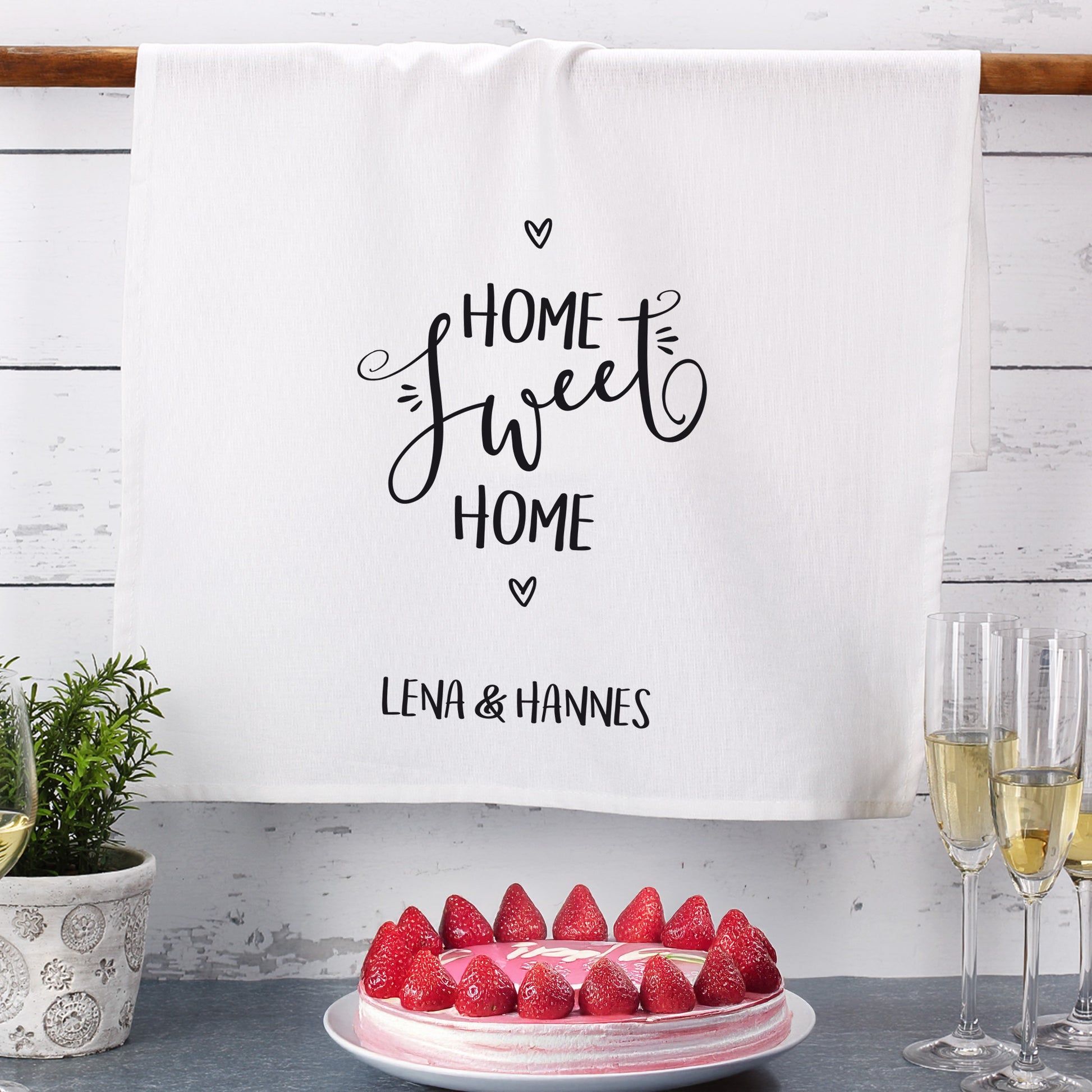 Geschirrtuch mit Namen Lena & Hannes, dekorativ am Regal mit Erdbeerkuchen und Sektgläsern