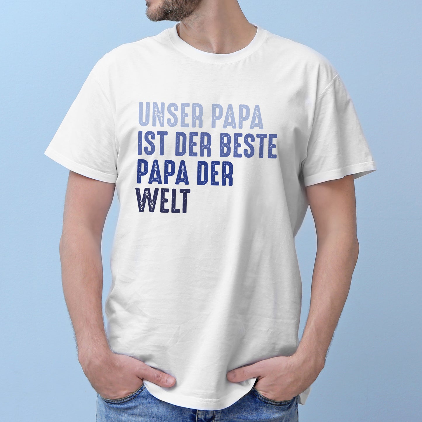 Mann mit weißem T-Shirt vor blauer Wand, Text: „Unser Papa – ist der beste – Papa der – Welt“