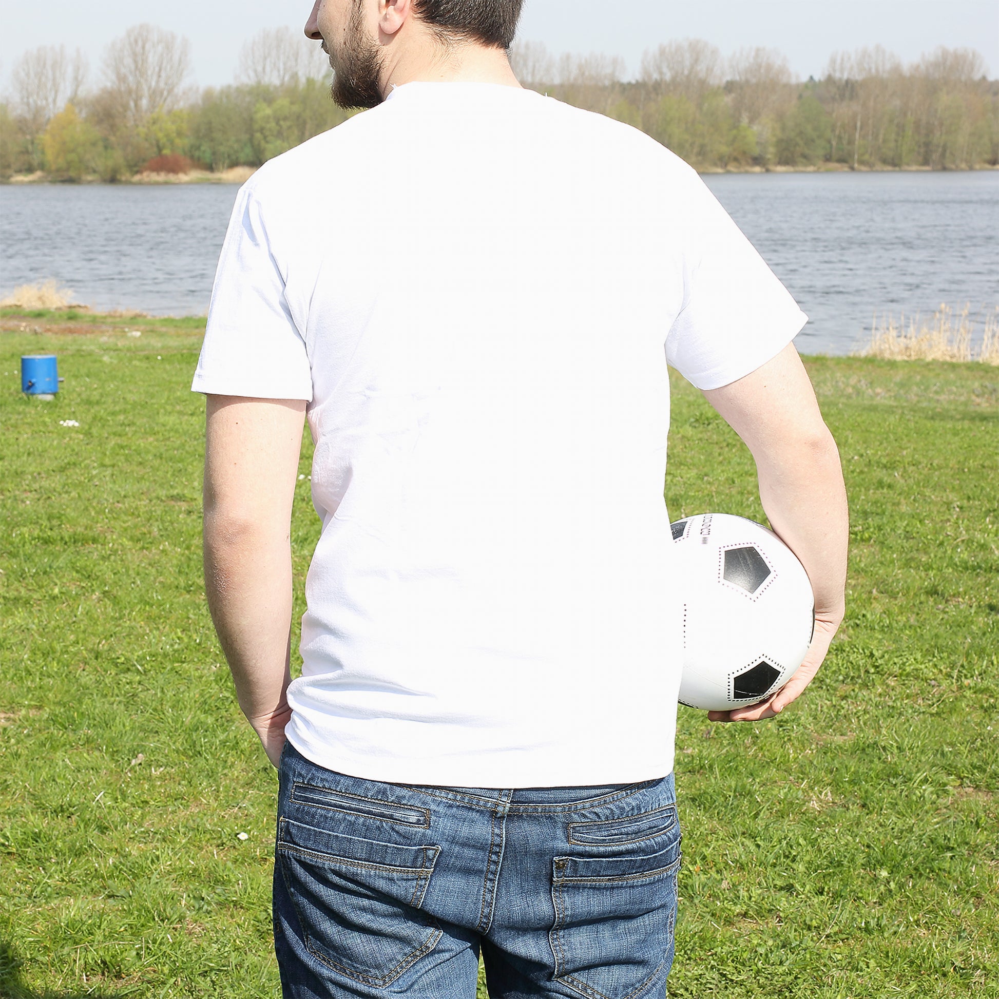 Rückansicht eines Mannes im weißen T-Shirt mit Fußball am See