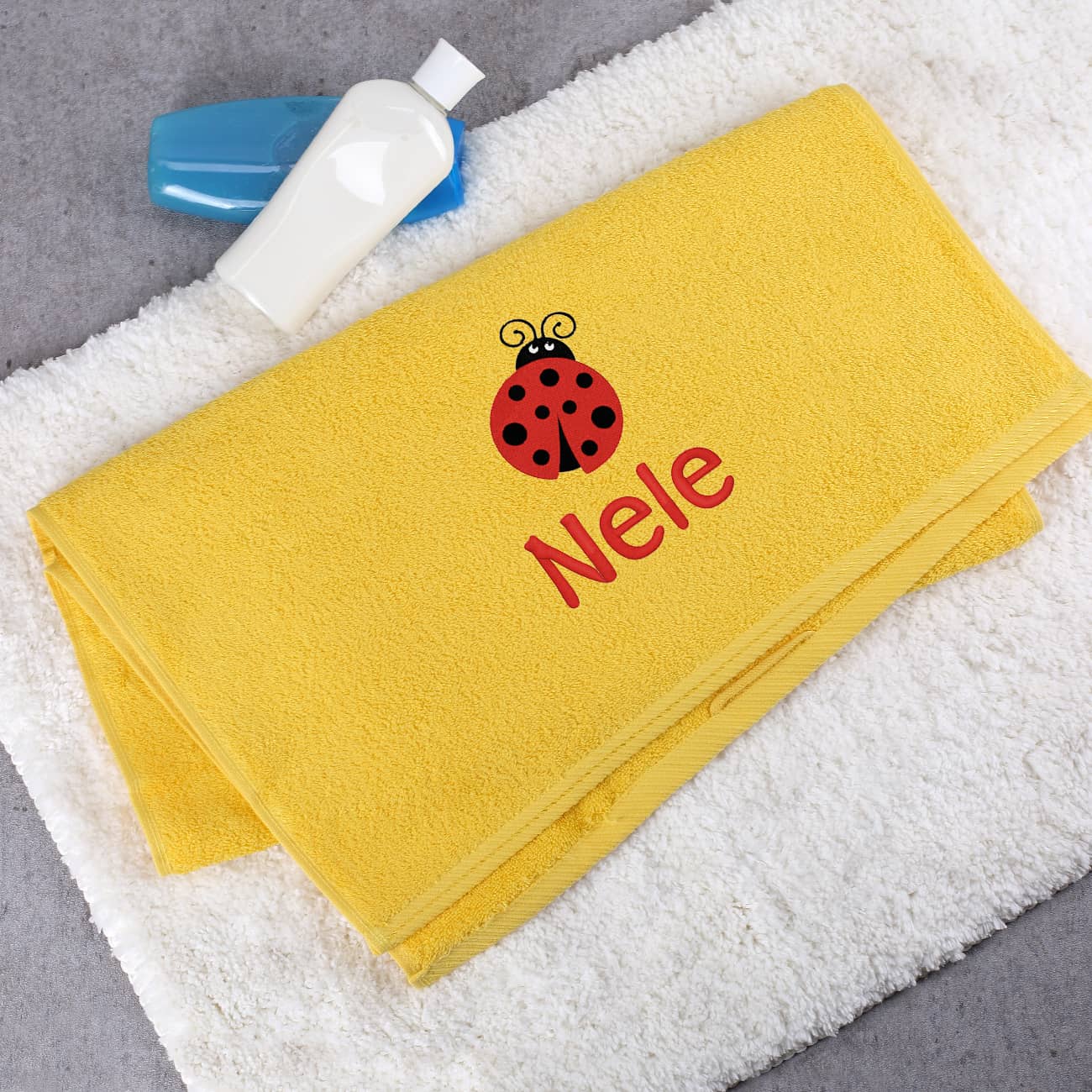 Gelbes Badehandtuch mit Marienkäfer und Name bestickt