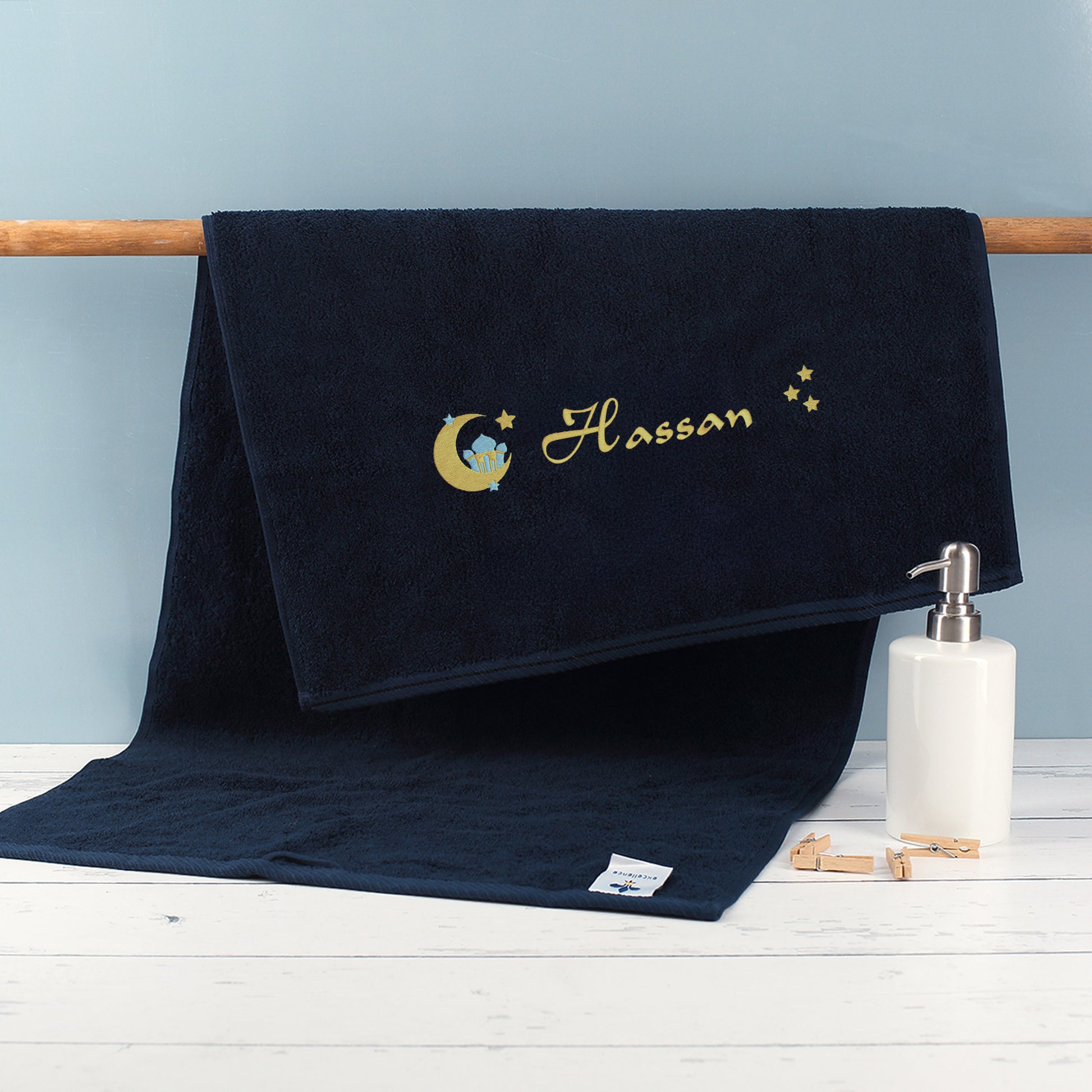 Nachtblaues Handtuch in drei Größen mit Ramadan-Motiv und Name Hassan bestickt am Handtuchhalter im Badezimmer