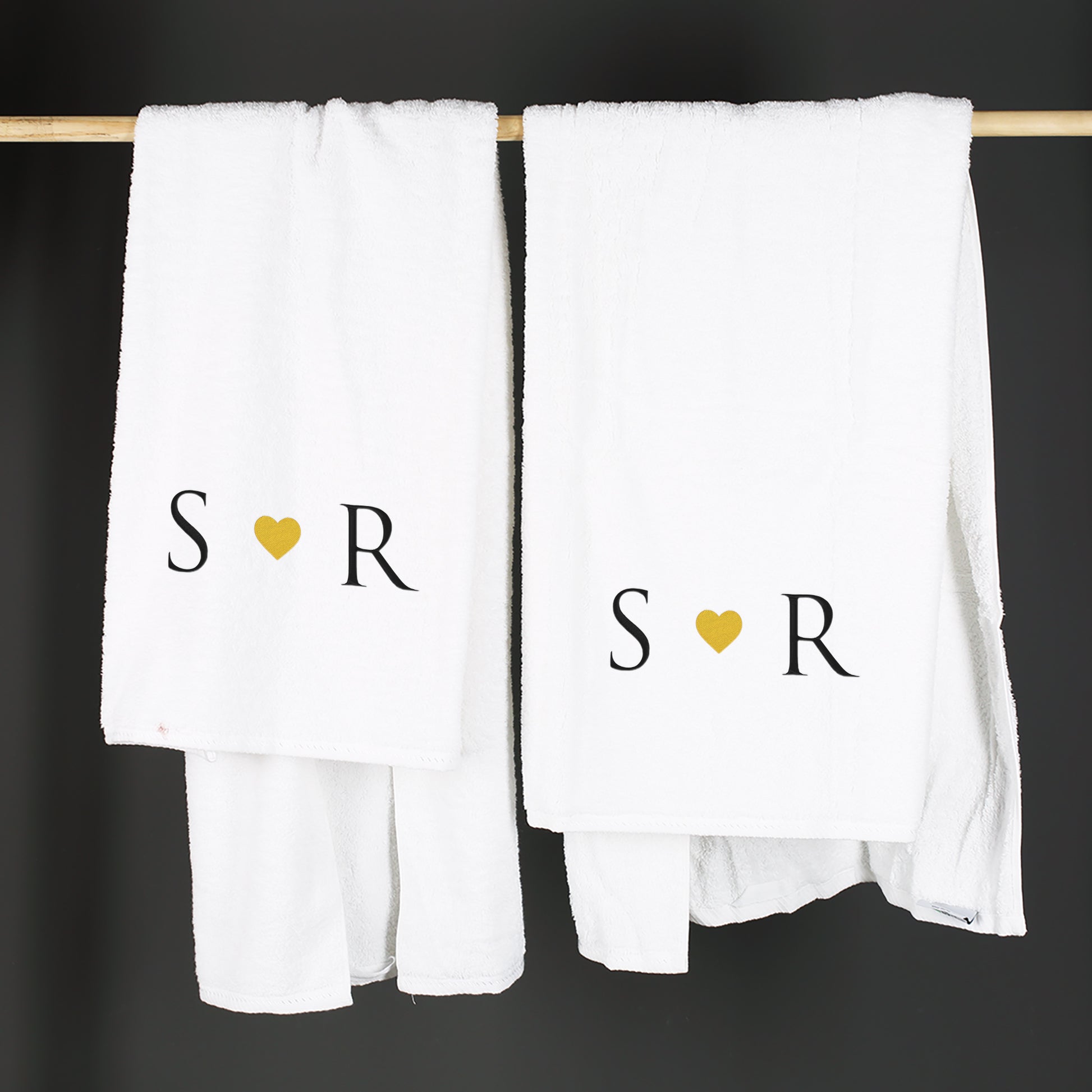 Zwei personalisierte Handtücher mit Initialen und Herz auf einer Stange hängend