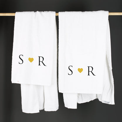 Zwei personalisierte Handtücher mit Initialen und Herz auf einer Stange hängend