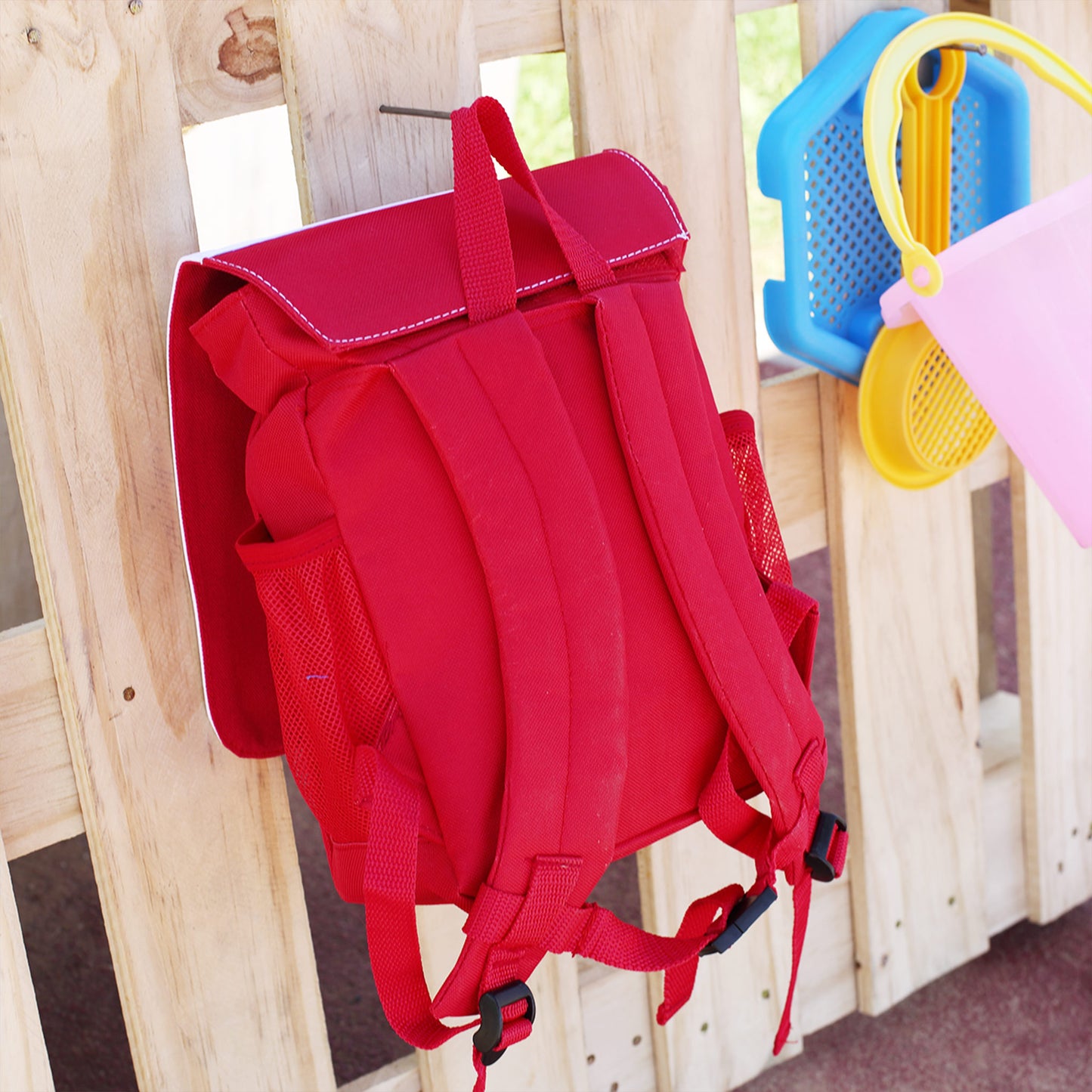 Rückseite des roten Kindergartenrucksacks mit gepolsterten Trägern und seitlichen Netzfächern