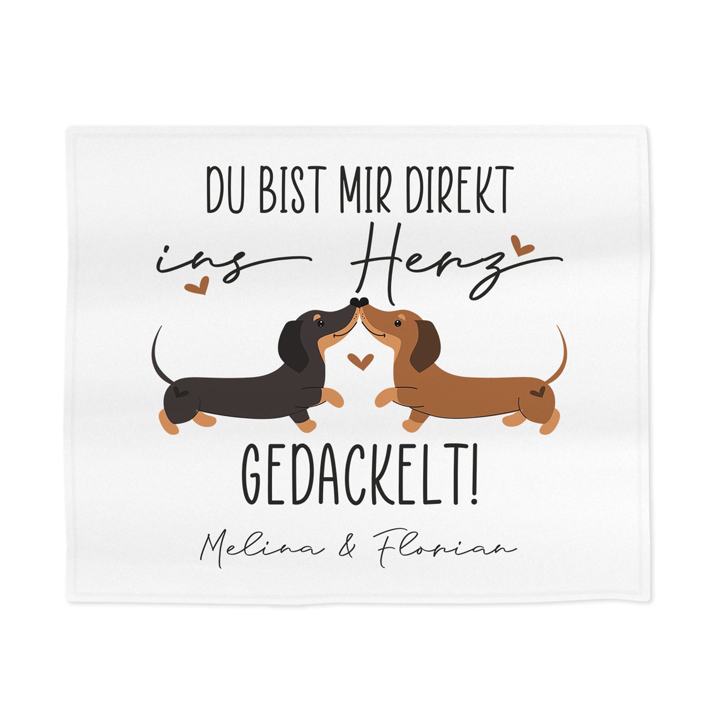 Detailansicht der personalisierten Kuscheldecke mit zwei küssenden Dackeln, Herzsymbolen und Spruch „Du bist mir direkt ins Herz gedackelt!“ – Fokus auf Motiv und Schrift