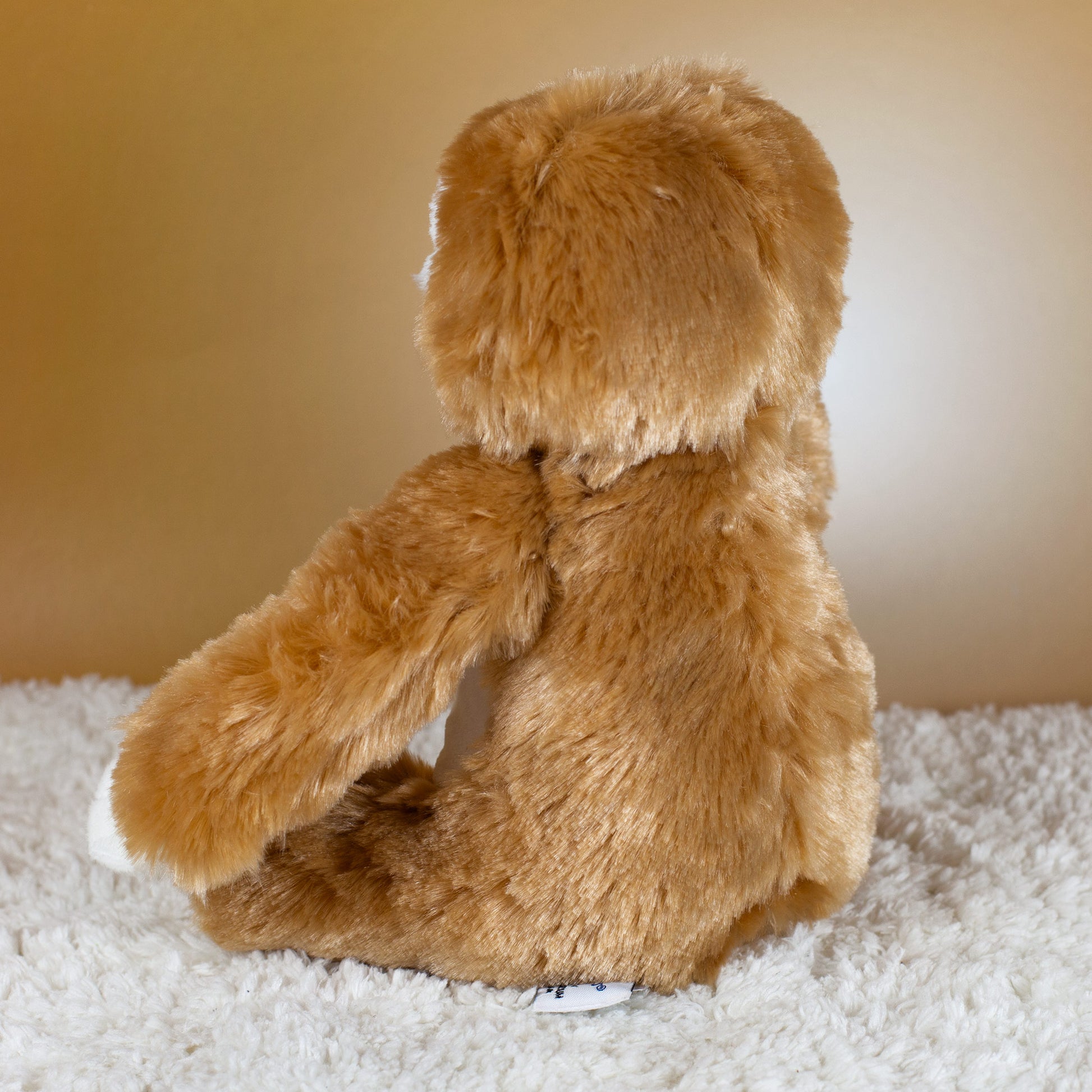 Rückansicht des flauschigen Faultier-Kuscheltiers auf hellem Untergrund.