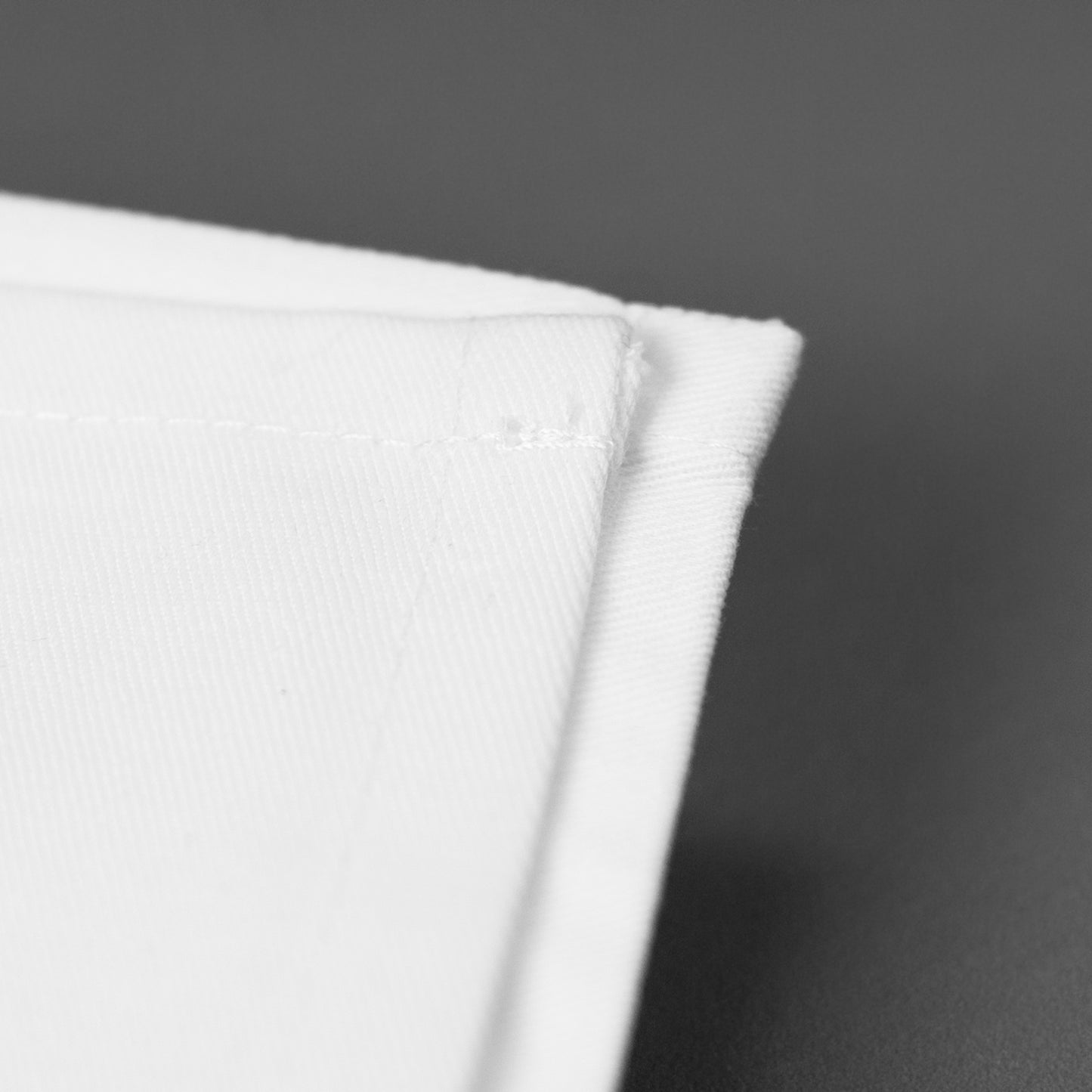 Detailaufnahme einer weißen Baumwollserviette mit sauber vernähter Kante