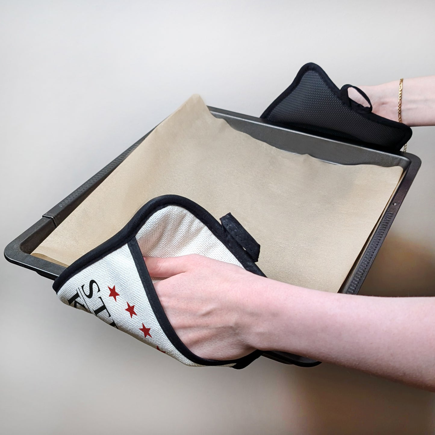 Topflappen im Einsatz – zwei Hände halten ein heißes Blech mit den personalisierten Topflappen