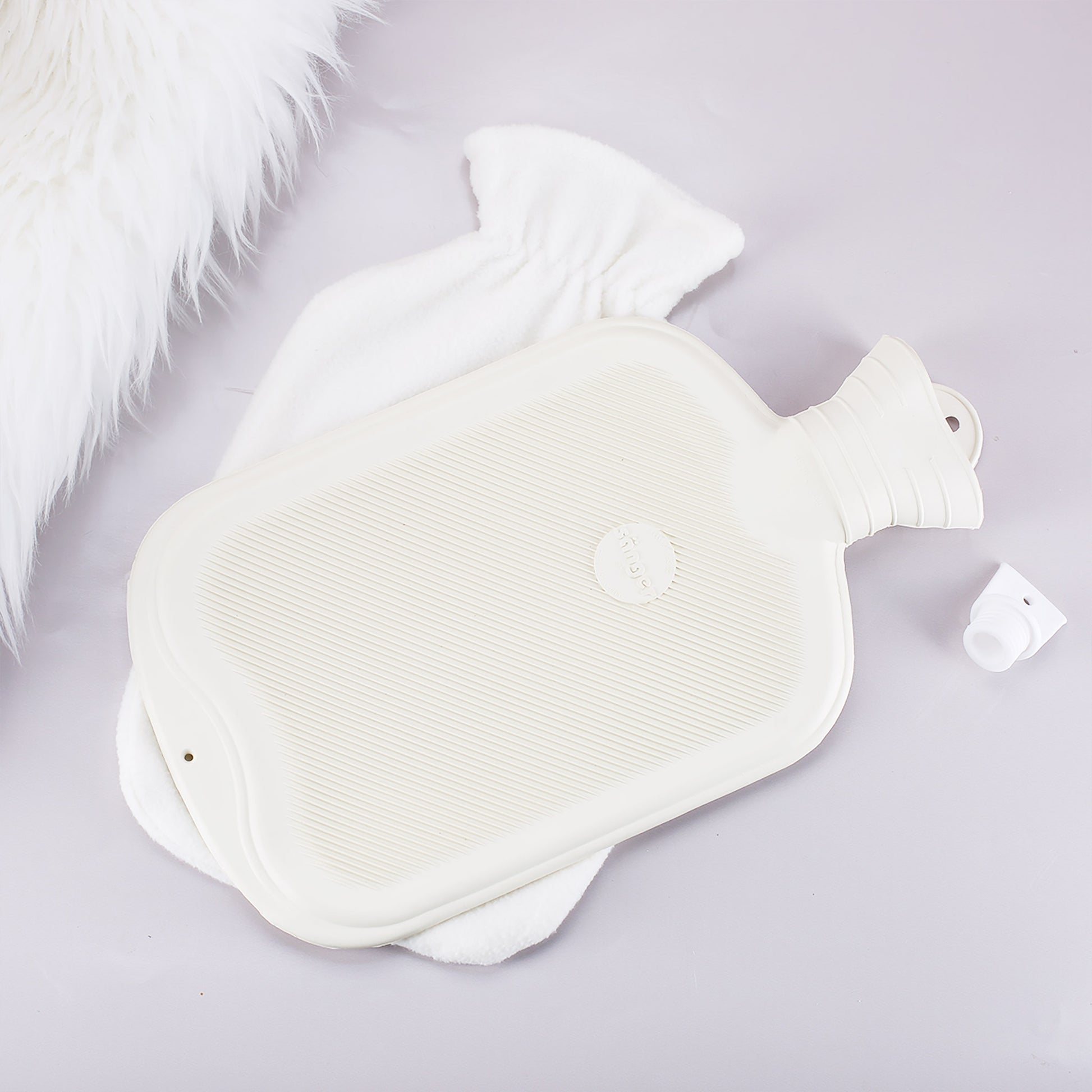 Rückseite der Wärmflasche mit herausgenommener Gummiflasche und weißem Fleece-Bezug