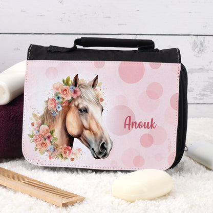 Schwarze Waschtasche mit Blumen-Pferdemotiv und Name „Anouk“ auf Teppich mit Seife und Kamm