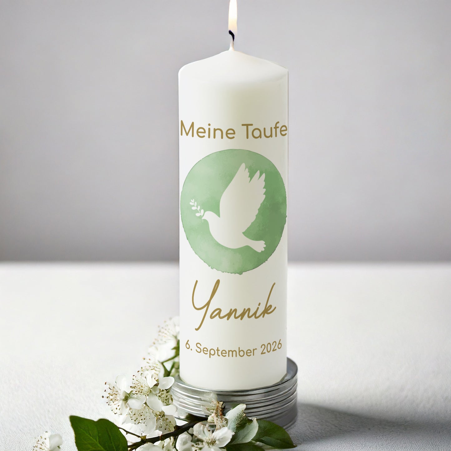 Personalisierte Taufkerze mit Taubenmotiv für Jungen und Mädchen. Die Kerze zeigt eine weiße Taube mit Olivenzweig auf einem grünen Aquarellhintergrund. Darüber steht in goldener Schrift „Meine Taufe“, darunter der Name „Yannik“ und das Taufdatum „6. September 2026“. Die Kerze brennt und steht auf einem silbernen Untersetzer, umgeben von weißen Blüten und grünen Blättern, vor einem schlichten grauen Hintergrund.