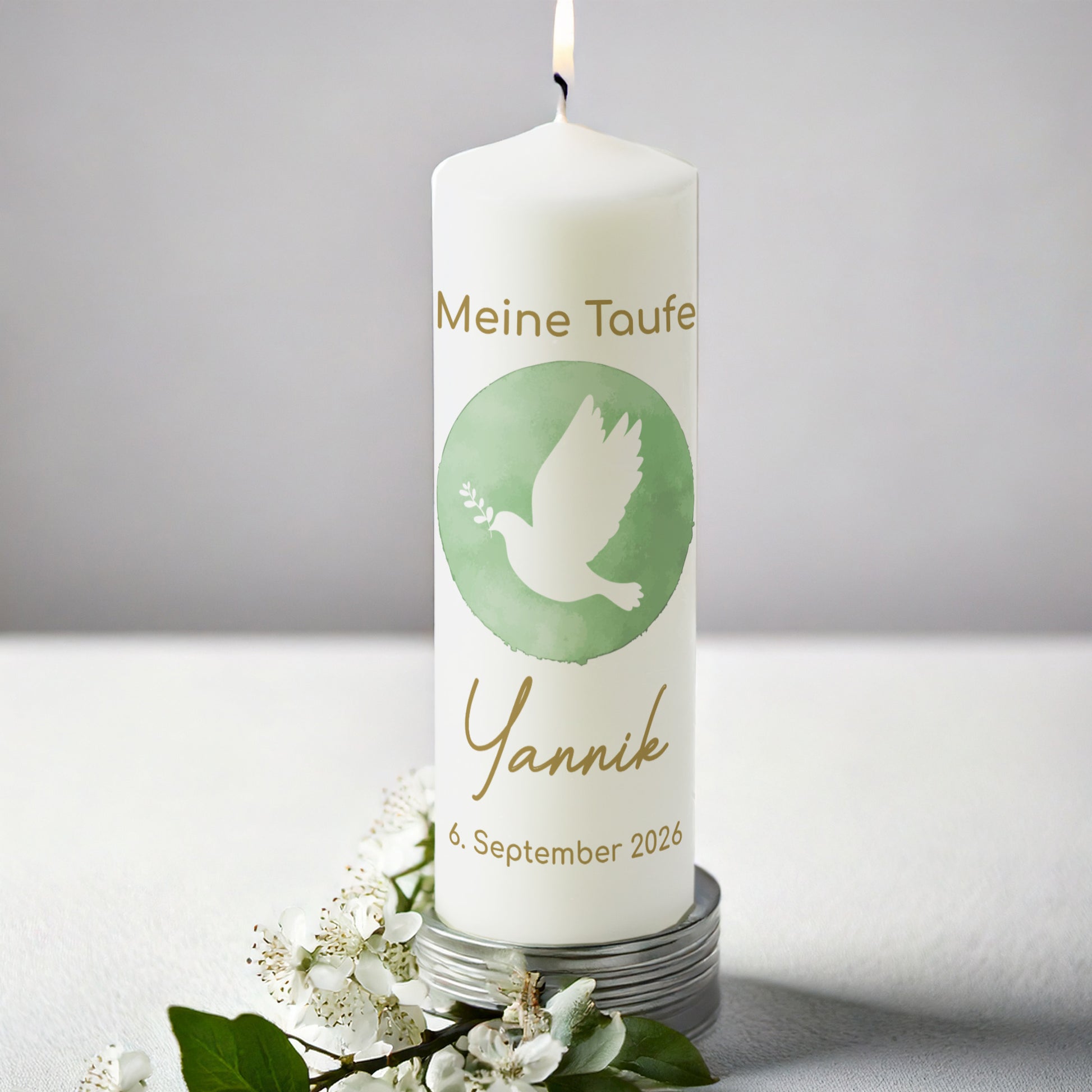 Personalisierte Taufkerze mit Taubenmotiv für Jungen und Mädchen. Die Kerze zeigt eine weiße Taube mit Olivenzweig auf einem grünen Aquarellhintergrund. Darüber steht in goldener Schrift „Meine Taufe“, darunter der Name „Yannik“ und das Taufdatum „6. September 2026“. Die Kerze brennt und steht auf einem silbernen Untersetzer, umgeben von weißen Blüten und grünen Blättern, vor einem schlichten grauen Hintergrund.
