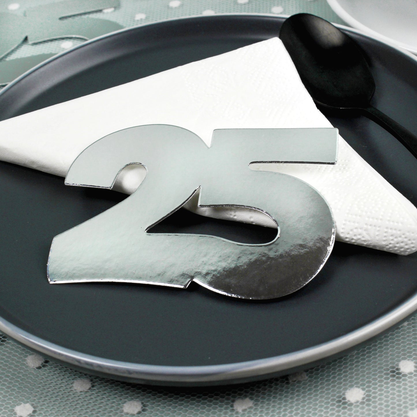 Jumbo-Konfetti Zahl 25 in Silber auf schwarzem Teller mit Serviette als elegante Tischdeko