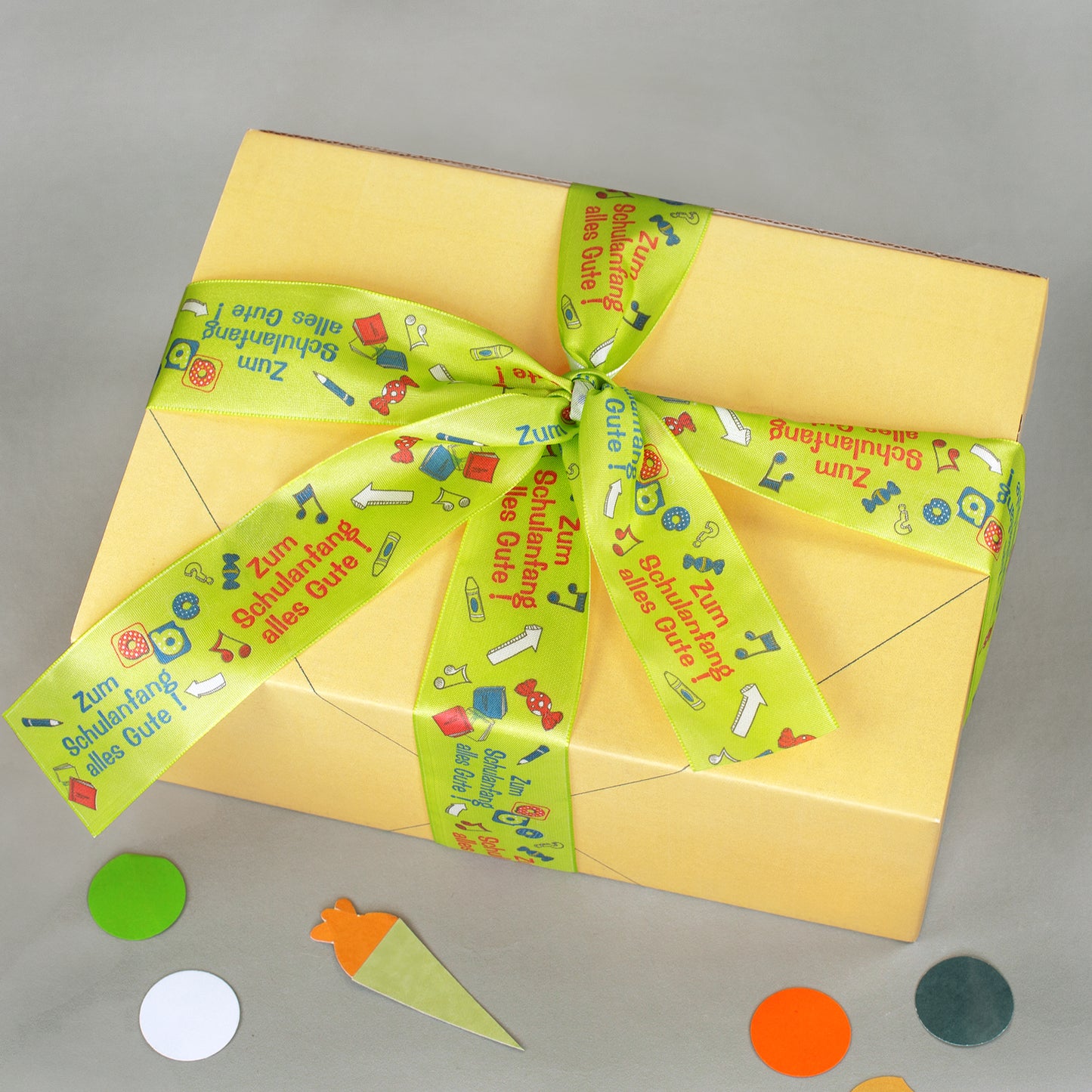 Gelbe Geschenkbox von oben mit Schleife aus Geschenkband für Schulanfang und Einschulung